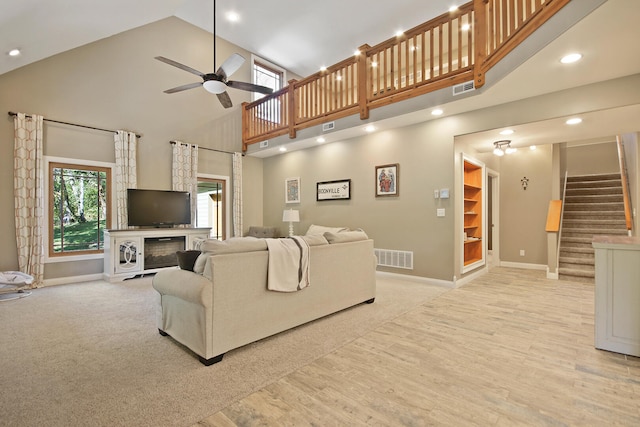 living room with ceiling fan, light wood-type flooring, and high vaulted ceiling