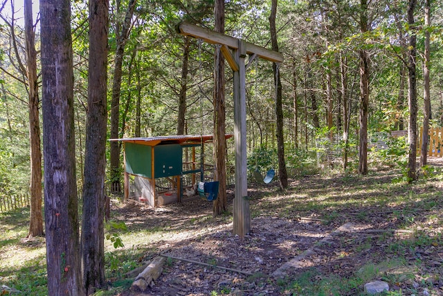 view of yard with an outdoor structure, a wooded view, and exterior structure