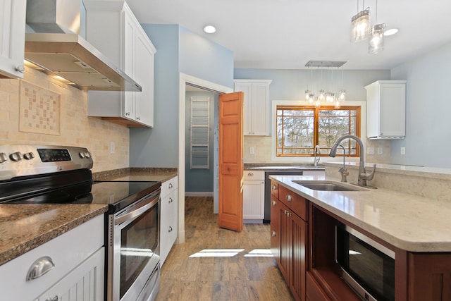 kitchen with wall chimney exhaust hood, appliances with stainless steel finishes, hanging light fixtures, and white cabinetry