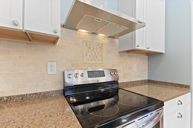 kitchen featuring range hood, stainless steel range with electric cooktop, light stone countertops, and white cabinetry