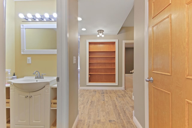 bathroom with built in shelves, wood finished floors, vanity, and baseboards