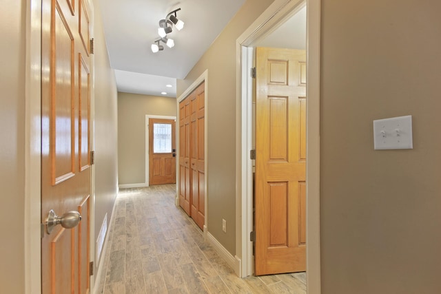 hallway with light wood-style flooring and baseboards