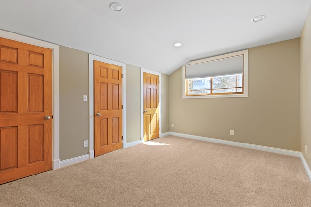 unfurnished bedroom featuring lofted ceiling, recessed lighting, baseboards, and light colored carpet