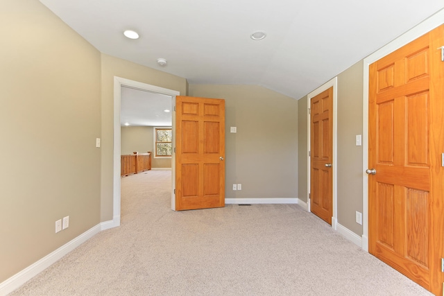 interior space with lofted ceiling, baseboards, and light colored carpet