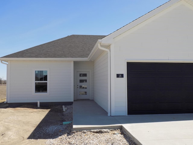 view of front of house featuring a garage and a shingled roof