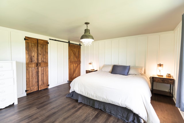 bedroom featuring dark wood-type flooring and a barn door