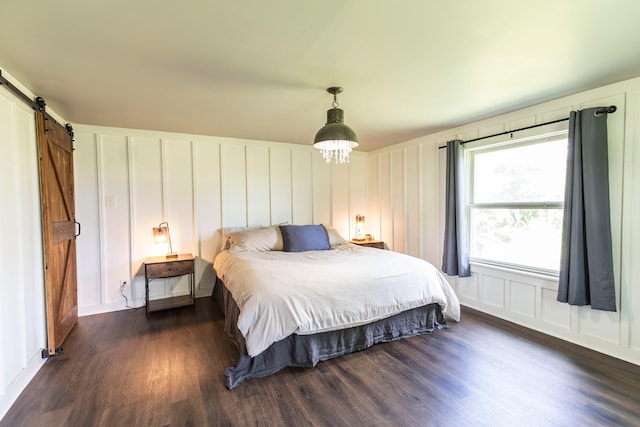 bedroom with dark wood-type flooring and a barn door