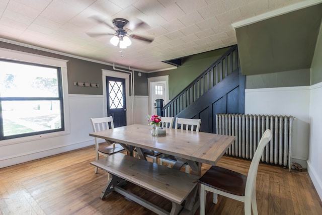 dining area featuring hardwood / wood-style floors, ornamental molding, ceiling fan, and radiator