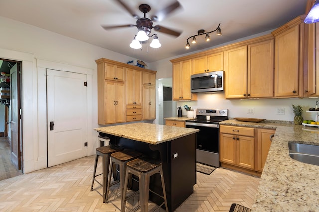 kitchen featuring ceiling fan, stainless steel appliances, light parquet flooring, and track lighting