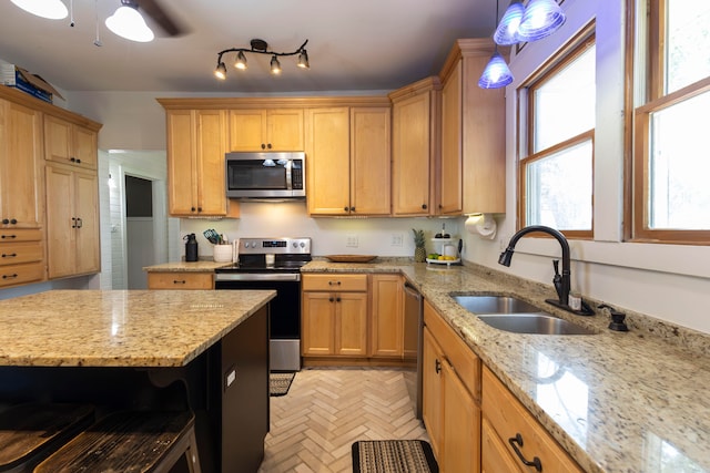 kitchen with sink, hanging light fixtures, light stone countertops, ceiling fan, and stainless steel appliances