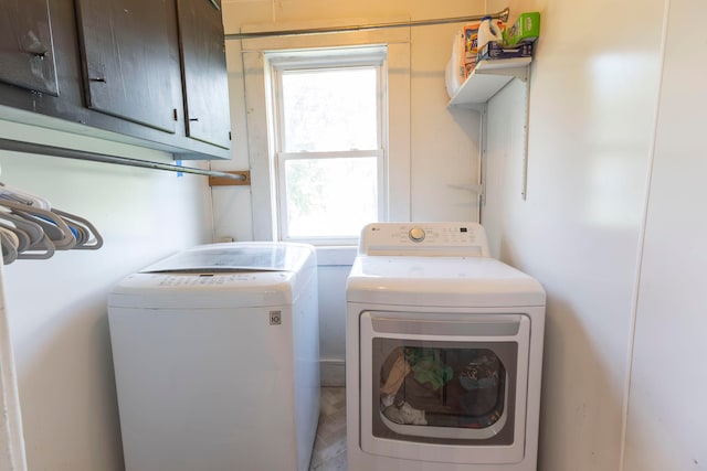 laundry area featuring a wealth of natural light, cabinets, and washer and clothes dryer