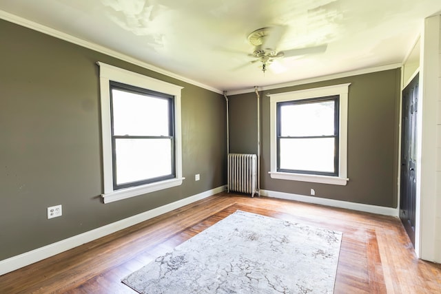 unfurnished room featuring ceiling fan, wood-type flooring, crown molding, and radiator