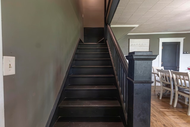 stairs featuring hardwood / wood-style floors and ornamental molding