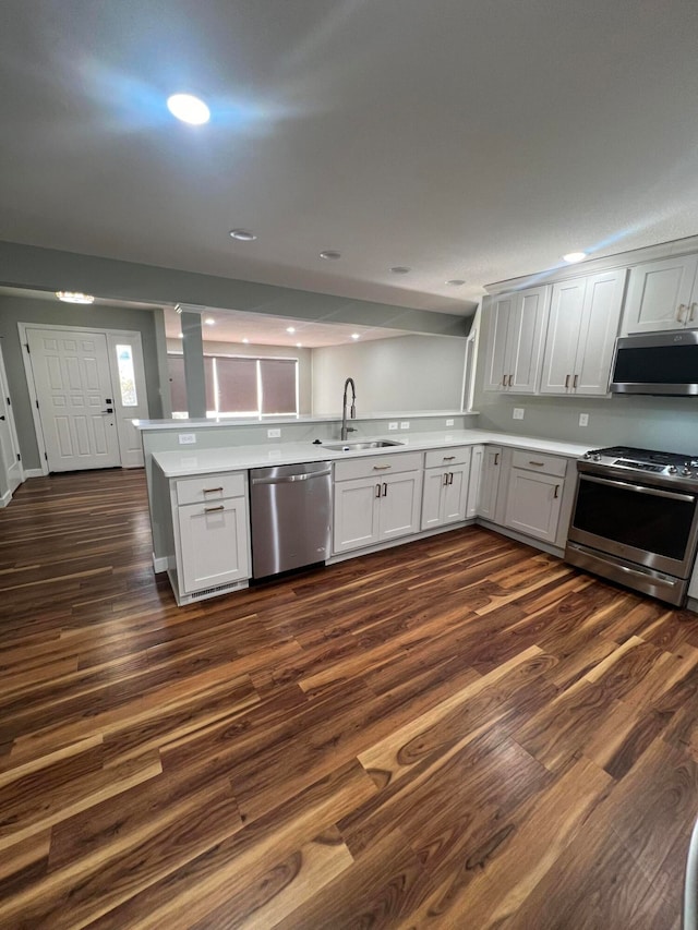 kitchen featuring dark wood-type flooring, kitchen peninsula, sink, and appliances with stainless steel finishes