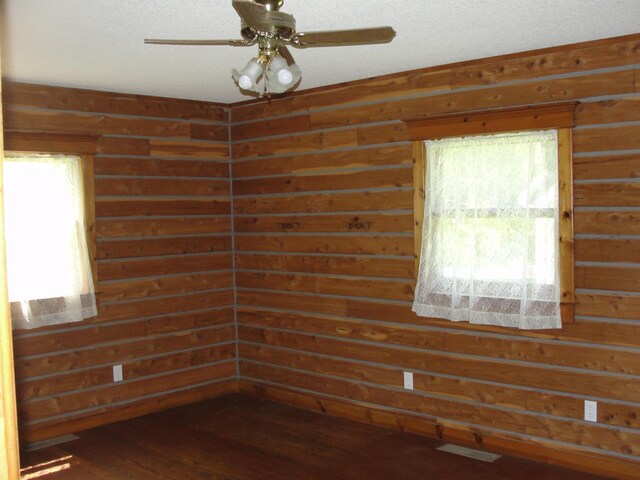 unfurnished room featuring ceiling fan, wooden walls, and hardwood / wood-style flooring