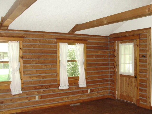 empty room featuring vaulted ceiling with beams and hardwood / wood-style flooring