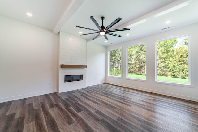 unfurnished living room with ceiling fan, beamed ceiling, dark hardwood / wood-style flooring, and a large fireplace