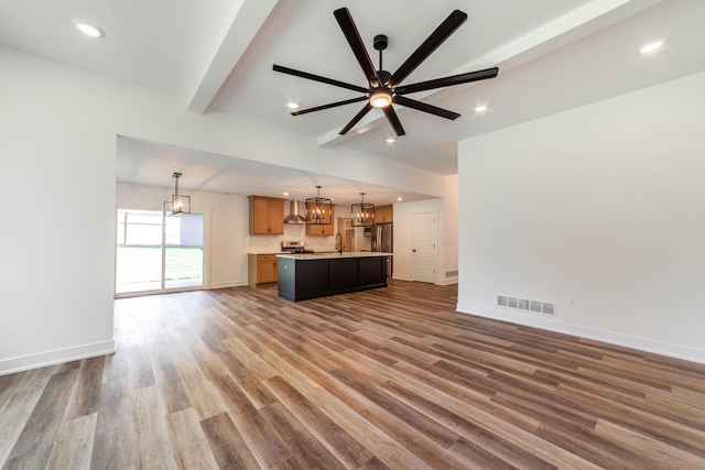 unfurnished living room featuring ceiling fan, beamed ceiling, sink, and dark hardwood / wood-style flooring