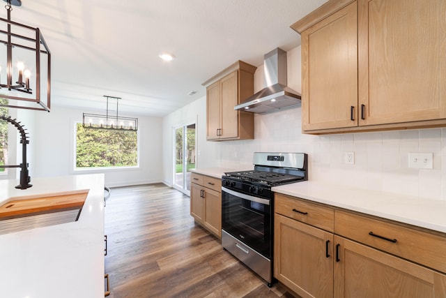 kitchen featuring pendant lighting, dark wood-type flooring, a notable chandelier, stainless steel range with gas stovetop, and wall chimney exhaust hood