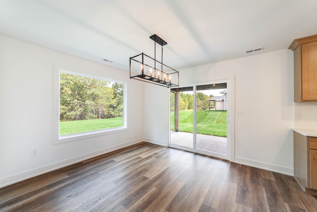 unfurnished dining area featuring a notable chandelier and dark hardwood / wood-style floors