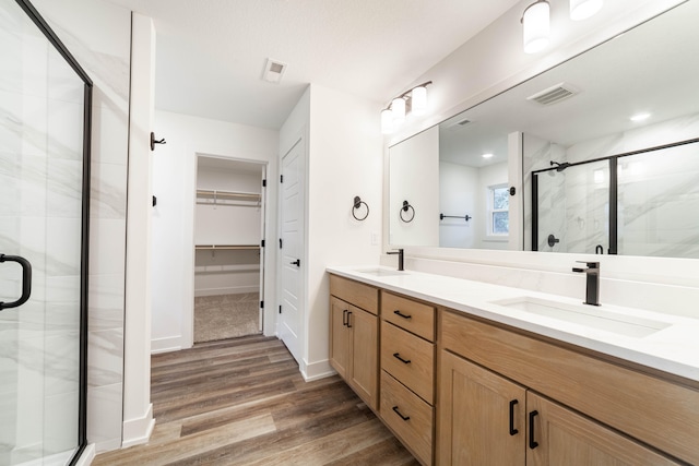 bathroom with walk in shower, vanity, and hardwood / wood-style floors