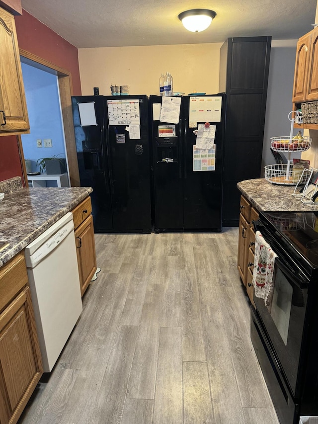 kitchen featuring black appliances, dark stone countertops, and light hardwood / wood-style floors