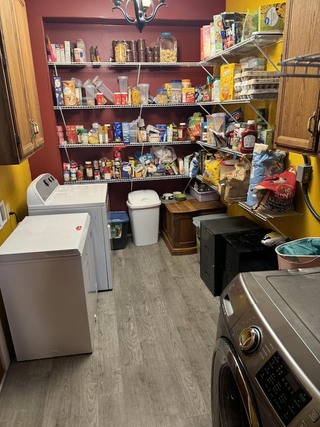 laundry room featuring light wood-type flooring, cabinets, and washing machine and clothes dryer