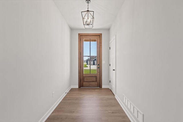 doorway featuring light hardwood / wood-style floors and a chandelier