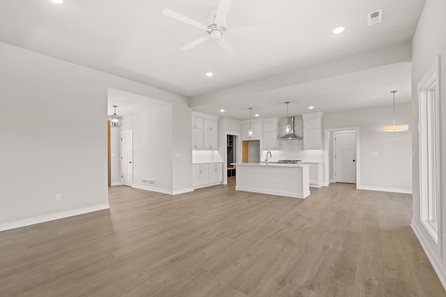 unfurnished living room with ceiling fan, sink, and light hardwood / wood-style floors