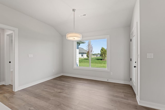 unfurnished dining area with baseboards, visible vents, wood finished floors, and lofted ceiling