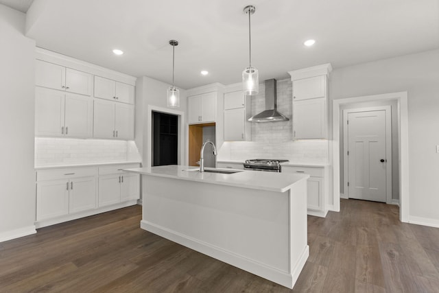 kitchen with pendant lighting, sink, an island with sink, white cabinetry, and wall chimney exhaust hood