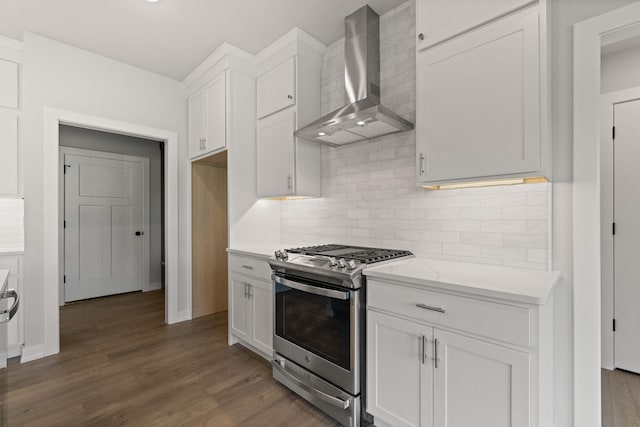 kitchen featuring tasteful backsplash, stainless steel range with gas stovetop, wall chimney range hood, white cabinets, and wood finished floors