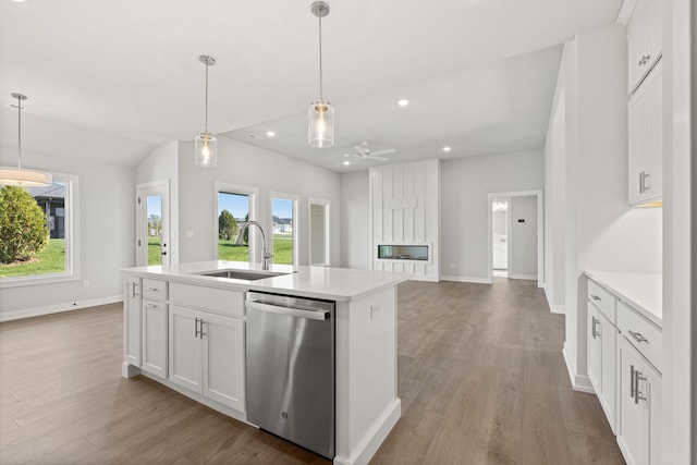 kitchen with white cabinets, sink, stainless steel dishwasher, a kitchen island with sink, and light hardwood / wood-style flooring