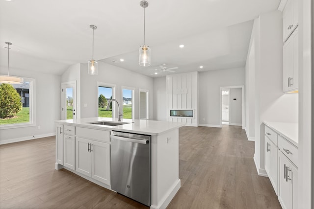 kitchen featuring light countertops, recessed lighting, a sink, dishwasher, and wood finished floors