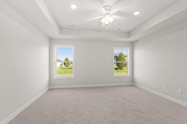 empty room with baseboards, visible vents, light carpet, and a raised ceiling