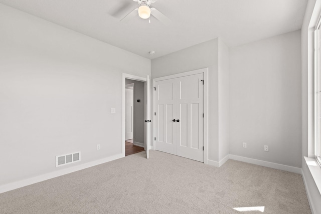 unfurnished bedroom with a closet, visible vents, baseboards, ceiling fan, and carpet floors
