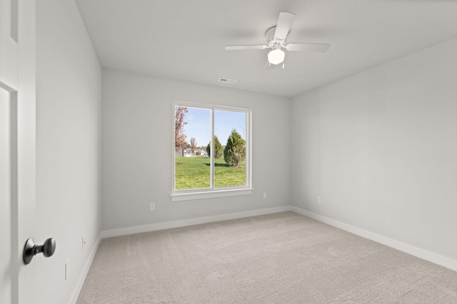 carpeted empty room with baseboards, ceiling fan, and visible vents