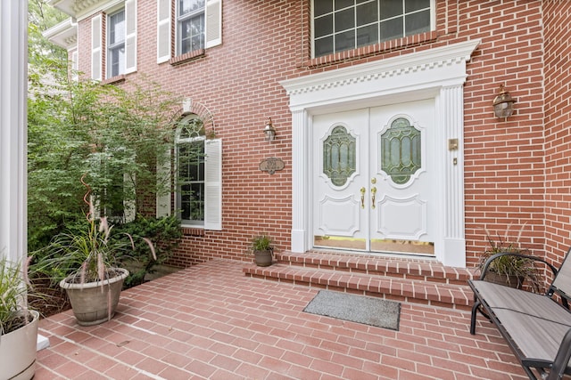 entrance to property with french doors, brick siding, and a patio