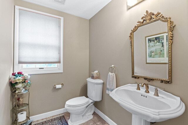 bathroom featuring visible vents, toilet, a sink, baseboards, and tile patterned floors