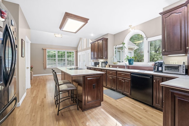 kitchen featuring a toaster, a kitchen island, a kitchen breakfast bar, light countertops, and black appliances