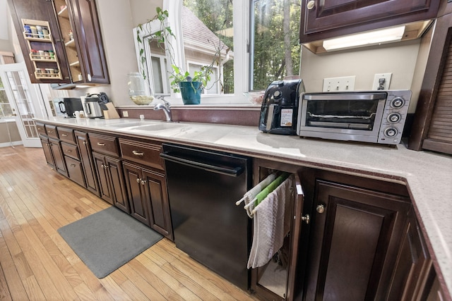 kitchen with a toaster, light wood finished floors, light countertops, a sink, and dishwasher