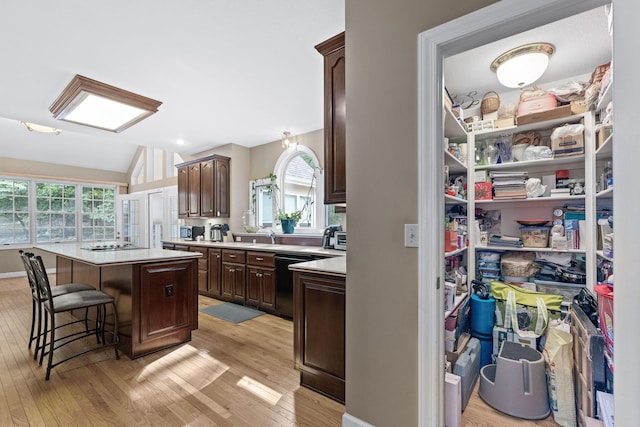 kitchen featuring a center island, light countertops, a healthy amount of sunlight, dark brown cabinets, and black appliances