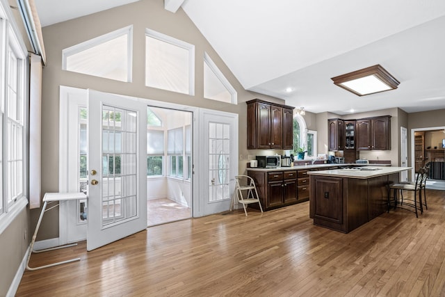 kitchen featuring a breakfast bar area, light countertops, a kitchen island, dark brown cabinets, and light wood-type flooring