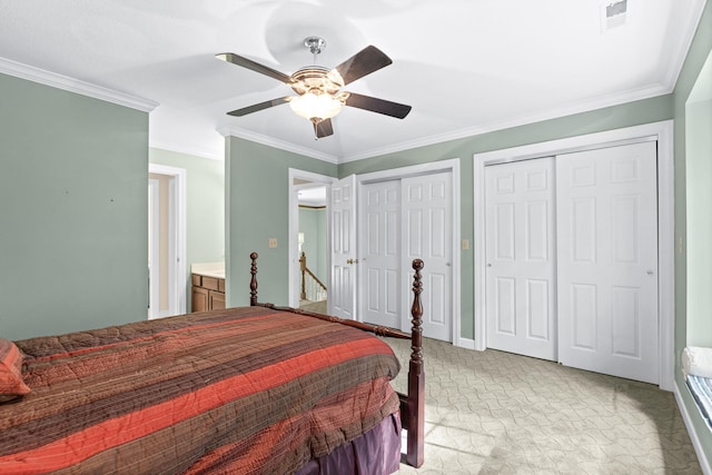 bedroom featuring crown molding, two closets, light colored carpet, visible vents, and a ceiling fan