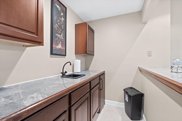 kitchen with light tile patterned floors, baseboards, tile counters, and a sink