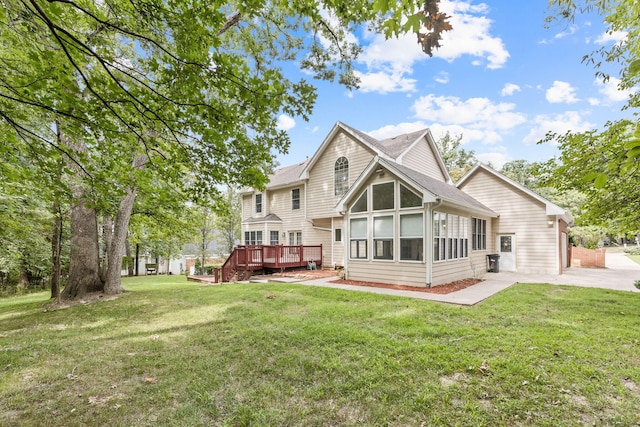 rear view of property featuring concrete driveway, roof with shingles, a lawn, and a wooden deck