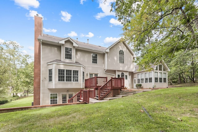 rear view of property with a yard, a chimney, a sunroom, a deck, and stairs