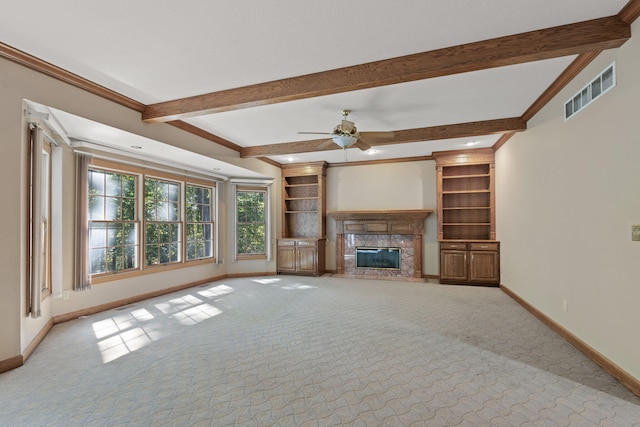 unfurnished living room with visible vents, a high end fireplace, light carpet, beamed ceiling, and baseboards