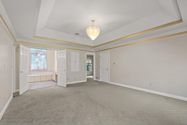 unfurnished room with a tray ceiling, crown molding, visible vents, carpet flooring, and baseboards