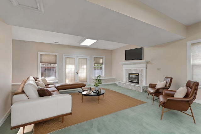 living room featuring carpet floors, a fireplace, baseboards, and french doors